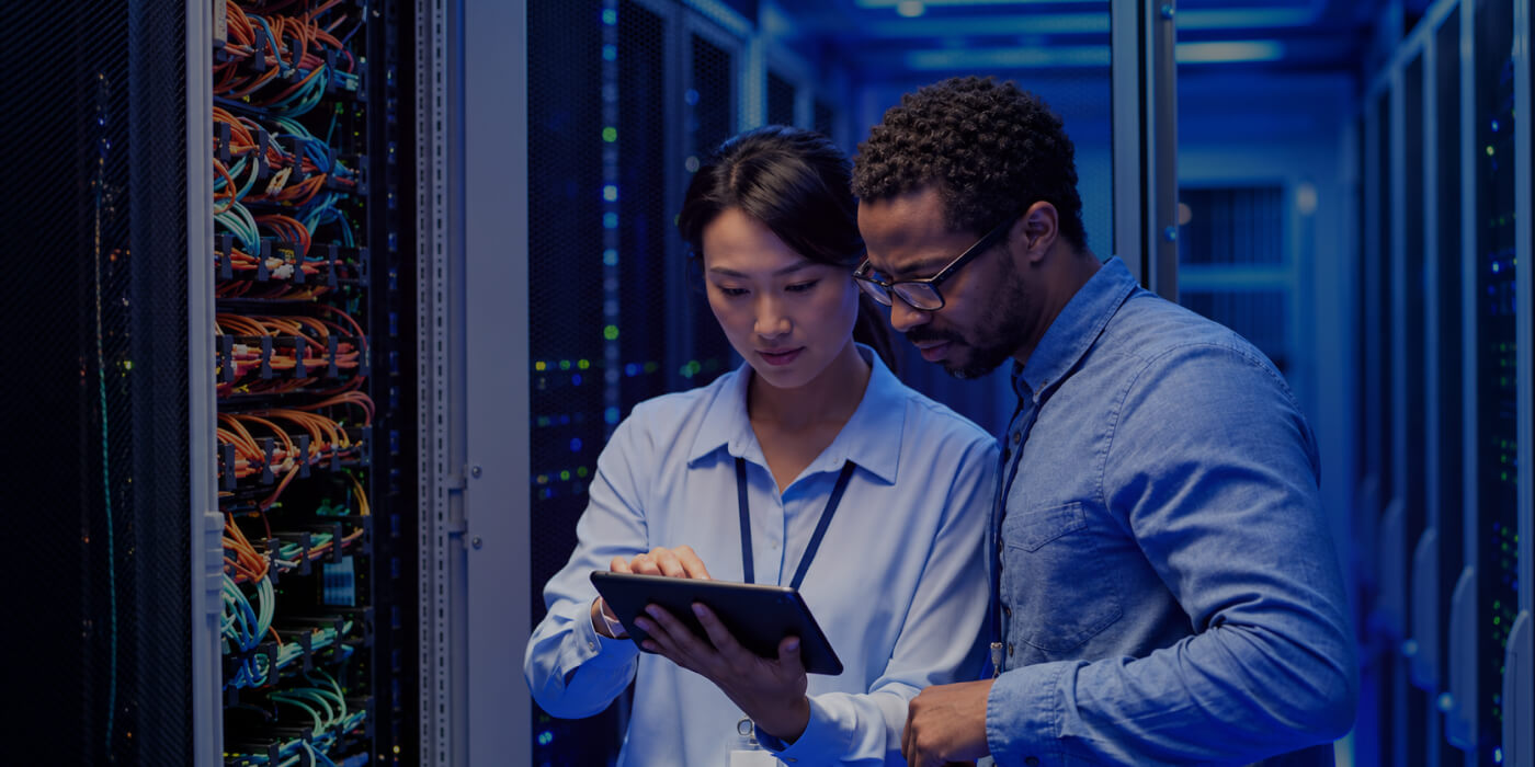 IT engineers reviewing cloud infrastructure on a tablet in a server room