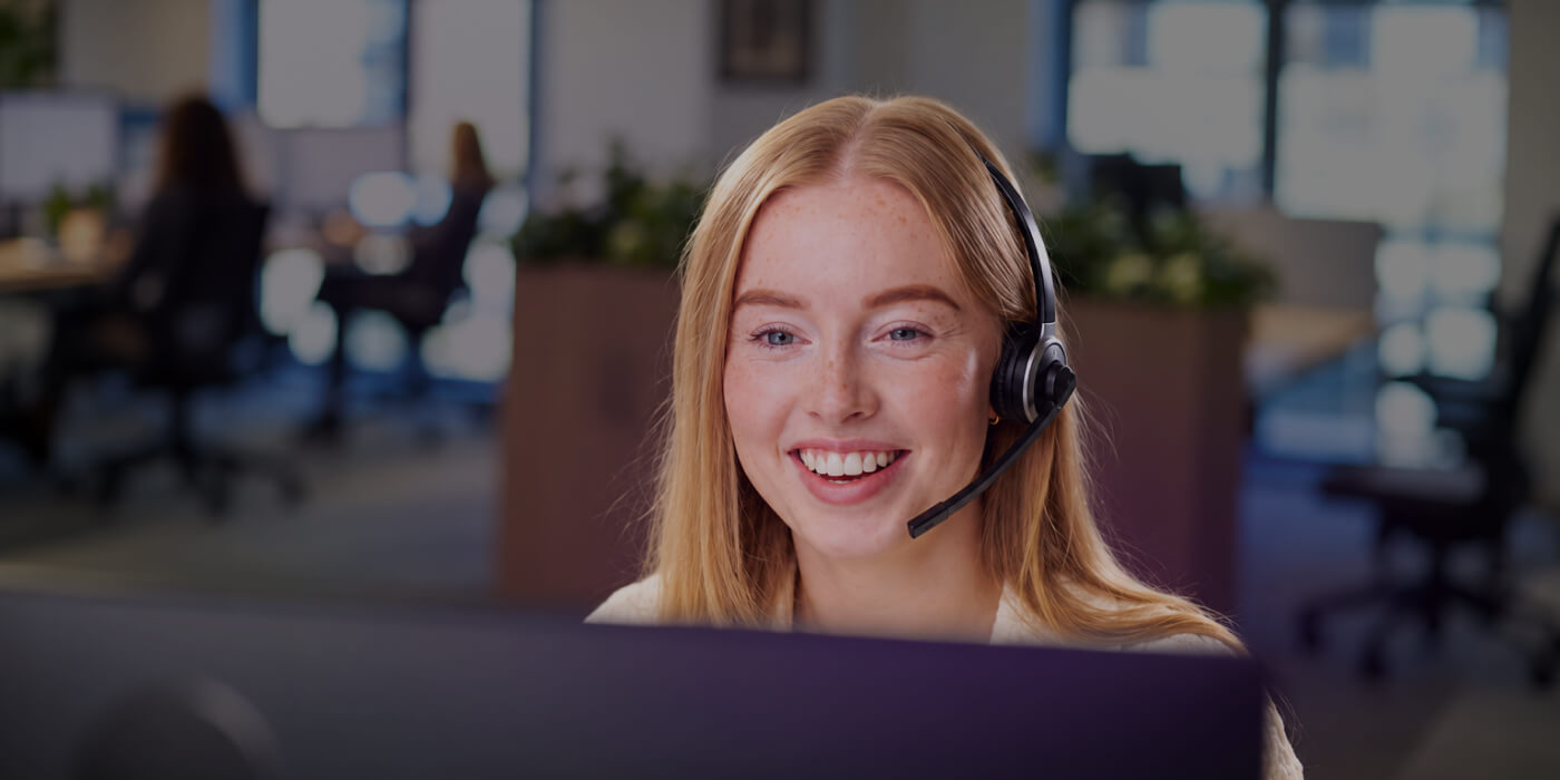 Smiling IT support specialist wearing a headset helping a client